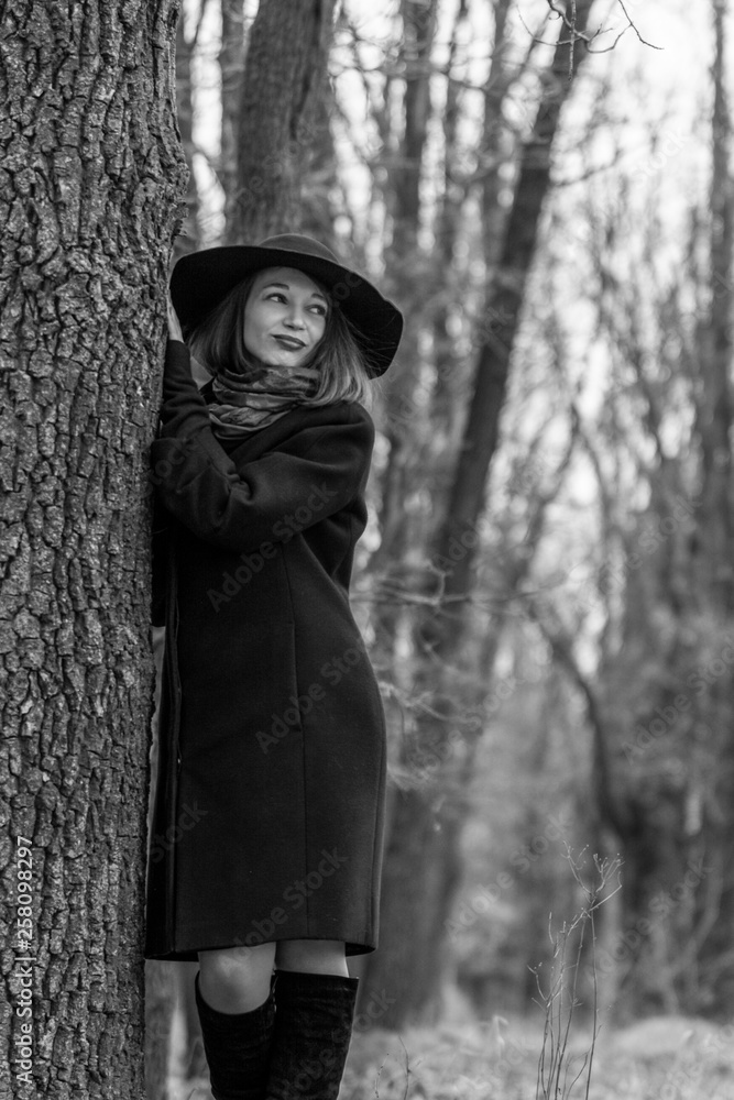 The young girl walks in the autumn park among trees in a black coat and hat. Red lipstick. Fashion and style. November. The young girl walks in the autumn park among trees in a black coat and hat. Red lipstick. Fashion and style. November.