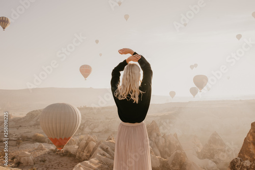 Bright woman on the background of balloons in Cappadocia in Turkey at sunrise