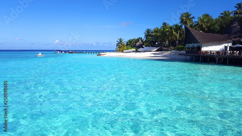 Crystal blue sea water at Maldives island on a sunny day with blue sky for the destination of summer holiday vacations concept.