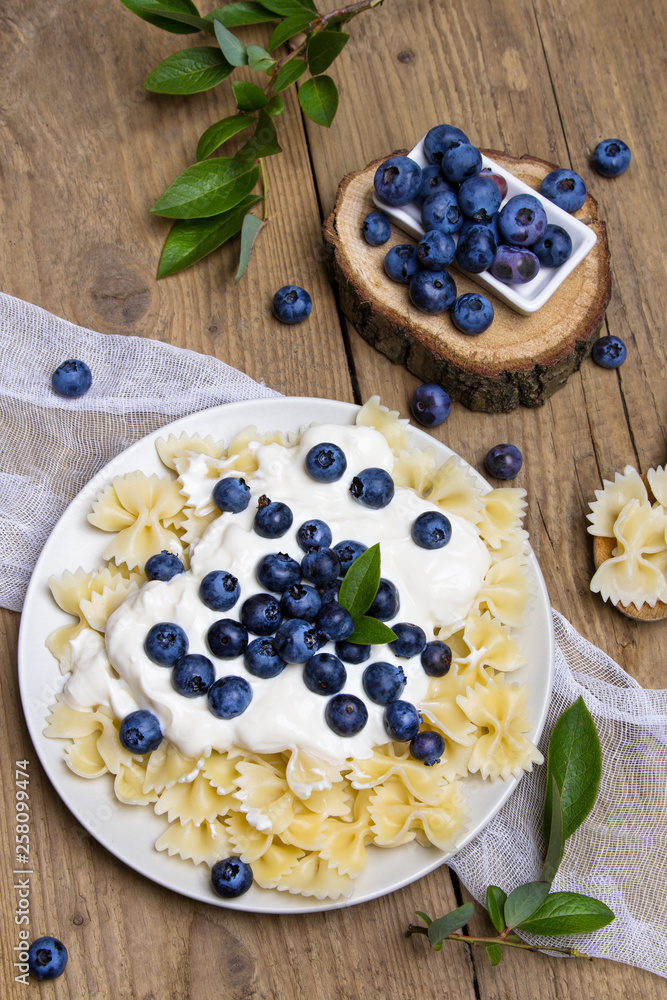 Tasty pasta with fresh organic blueberries and vanilla cream. Sweet dinner on retro wooden table. Tasty pasta with fresh organic blueberries and vanilla cream. Sweet dinner on retro wooden table.