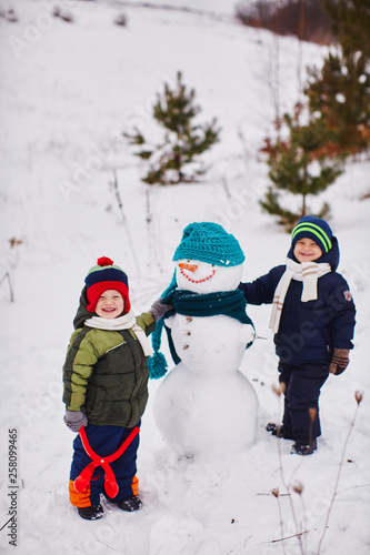 Two little boys are very happy and create a snowman