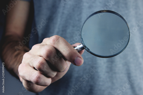 man holds magnifying glass in hand