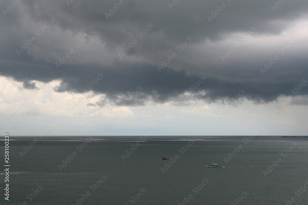 Storm gray clouds over calm gray sea.