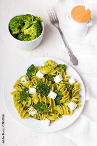 Tasty dinner. Green  pasta with broccoli, feta cheese and herb sauce on a white background.