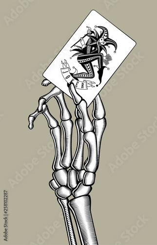 Skeleton hand holding Joker playing card