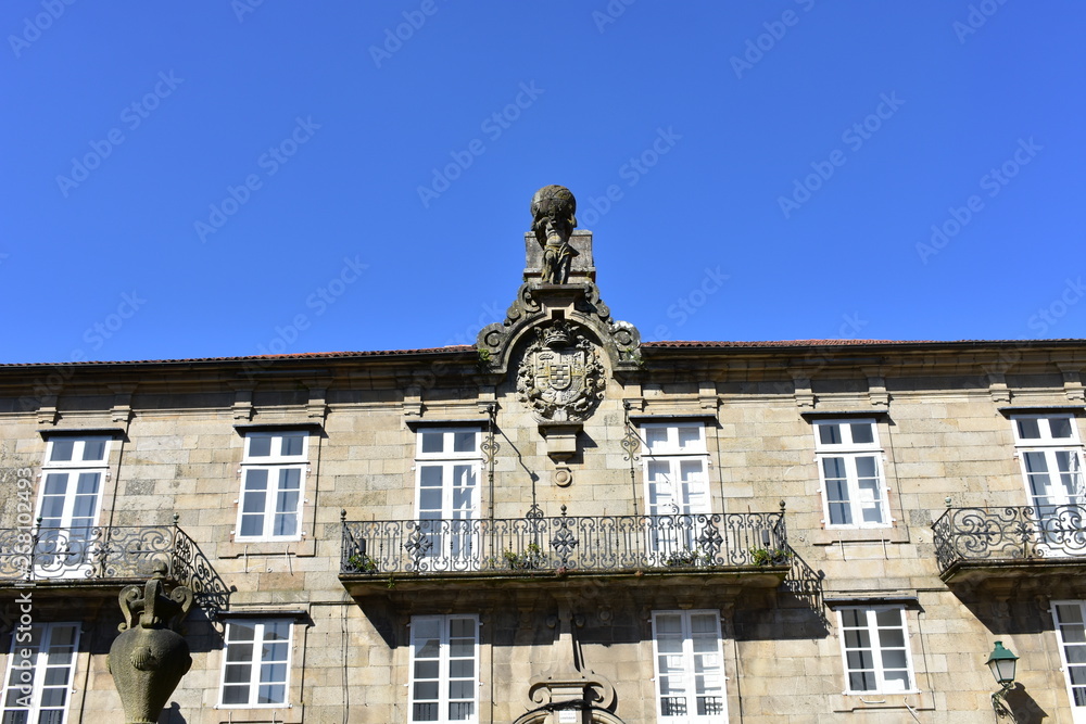 Building with Atlas sculpture, coat of arms and iron railings. Pazo de Bendaña. Plaza del Toural, Santiago de Compostela, Spain.