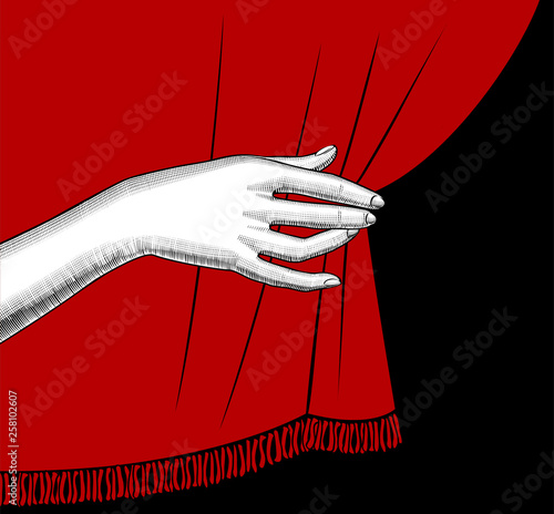 Female hand pulling aside the red curtain on black background