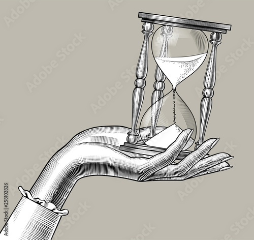 Female hand with a retro hourglass