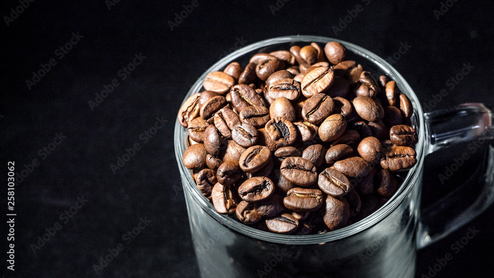 Fototapeta premium Glass cup of coffee with coffee beans on a dark background, close-up, in a low key