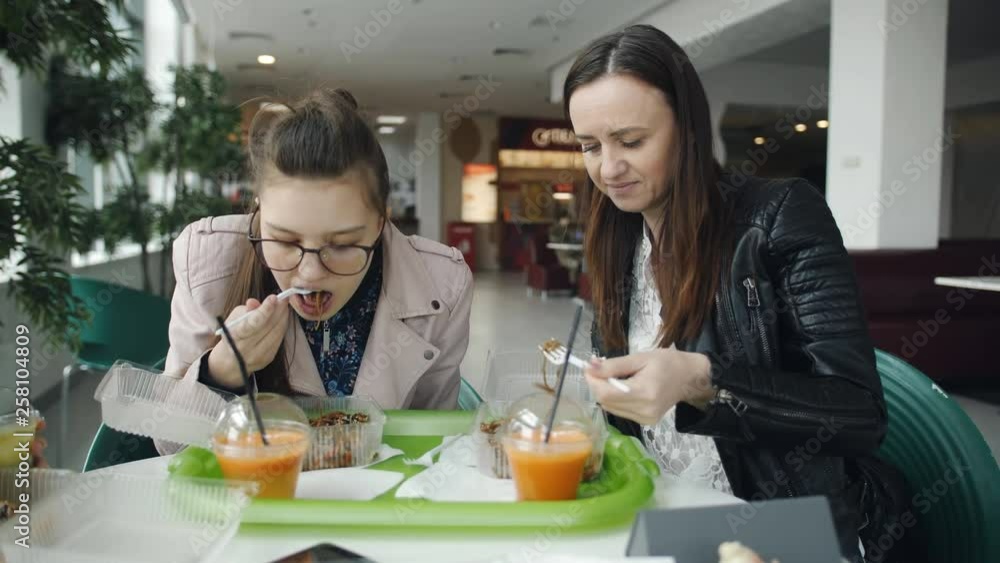 Mother and daughter a teenager in a cafe eating noodles and talking. Mother and daughter a teenager in a cafe eating noodles and talking.
