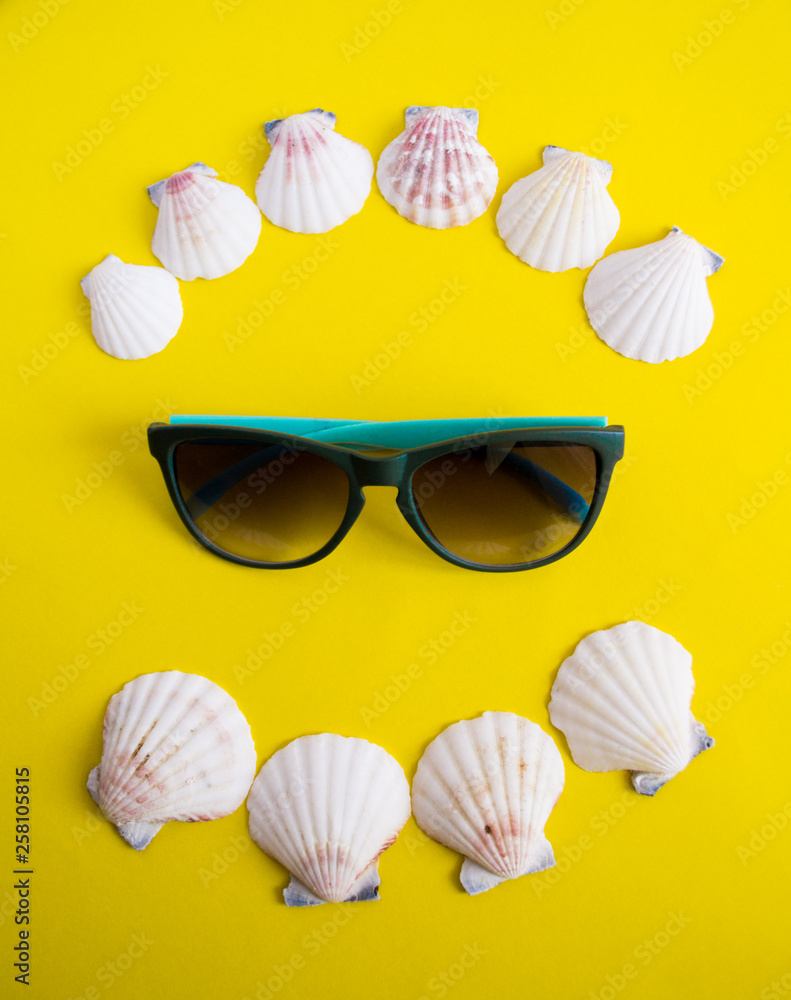 Obraz premium Semicircle of white seashells with sunglasses on yellow background