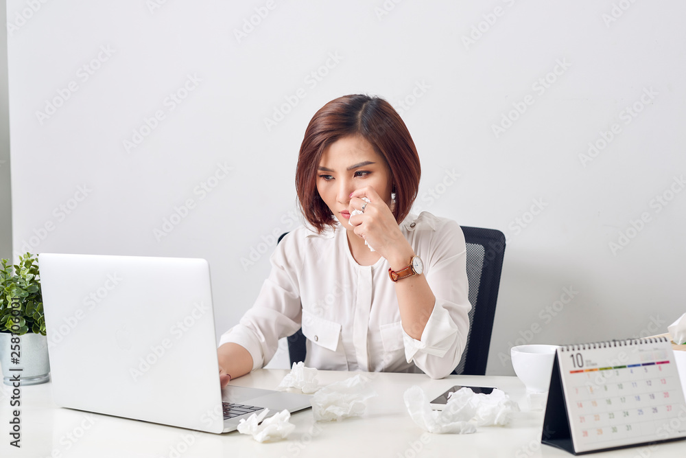 Sad exhausted woman with tissue suffering from cold while working with laptop at table Sad exhausted woman with tissue suffering from cold while working with laptop at table