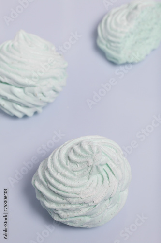 Homemade marshmallows laid on a white background. Marshmallow with mint, with a green tint. Nearby is a piece of marshmallow, its slice is visible.