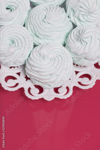 Homemade marshmallows laid on a plate. Marshmallow with mint, with a green tint. On the pink background.