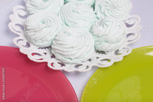 Homemade marshmallows laid on a plate. Marshmallow with mint, with a green tint. Nearby are plates of pink and light green.