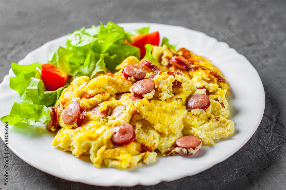Omelet with sausage and vegetables in white plate on Dark grey black slate background Omelet with sausage and vegetables in white plate on Dark grey black slate background