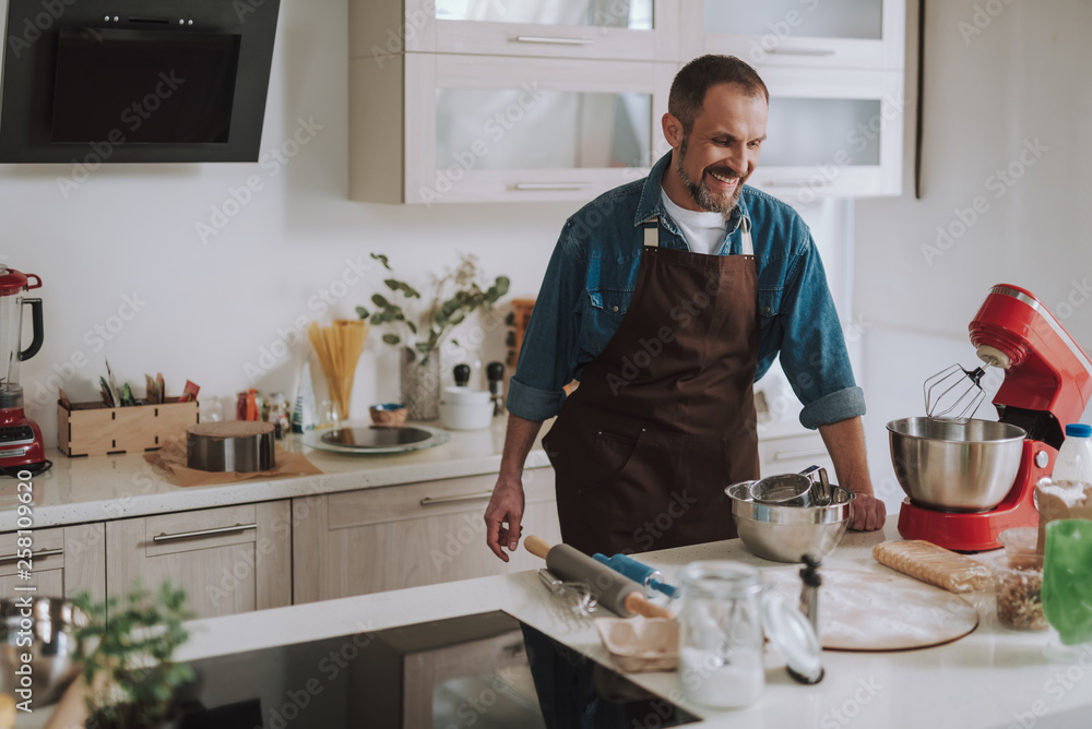 Happy bearded man laughing while looking at the mixer Happy bearded man laughing while looking at the mixer