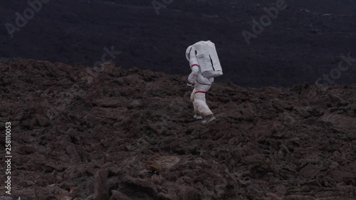 Astronaut walking in a Martian desolate landscape, Hawaii