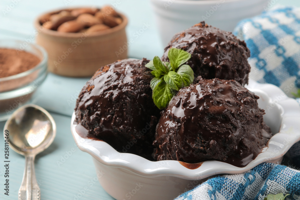 Chocolate ice cream with liquid chocolate and with a cinnamon stick, coffee beans and almonds on a blue wooden background. Chocolate ice cream with liquid chocolate and with a cinnamon stick, coffee beans and almonds on a blue wooden background.