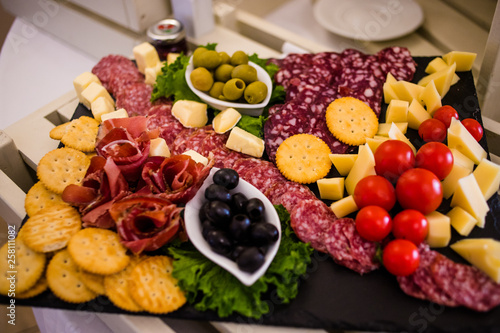Meat dish with ham, crackers, tomatoes, olives and sausage