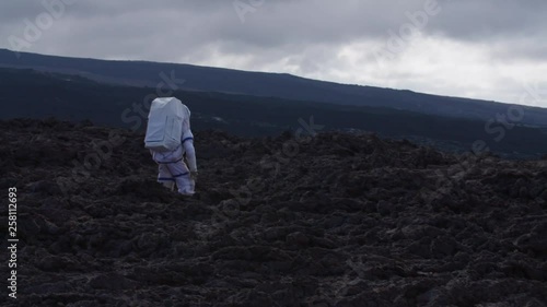 Astronaut walking in a Martian desolate landscape, Hawaii