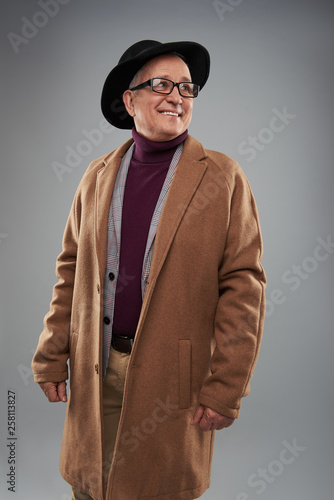 Adult man smiling while wearing long coat and hat photo