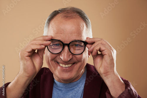 Mature man feeling confident while putting on his glasses
