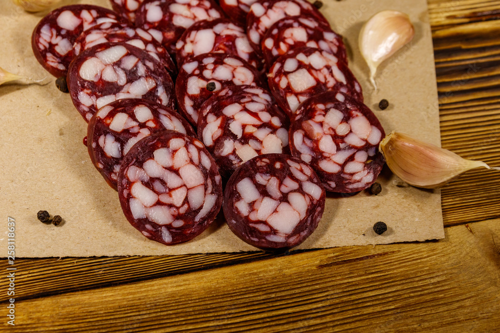 Sliced salami sausage on brown paper on wooden table Sliced salami sausage on brown paper on wooden table