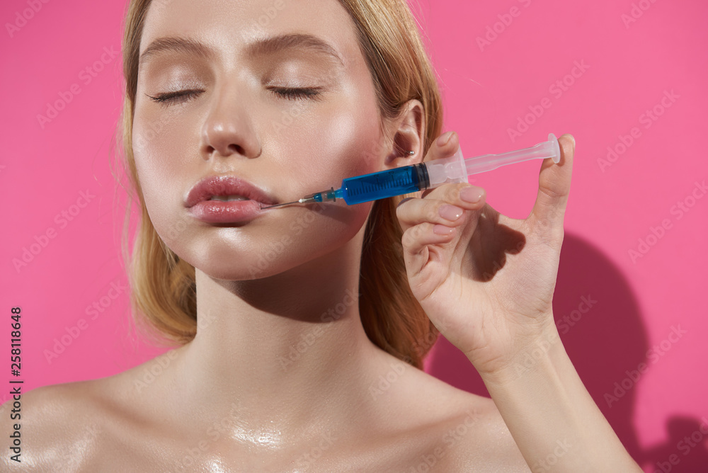 Young female having filler injection for lips Young female having filler injection for lips