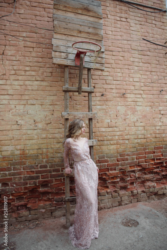 Young woman in a long pink dress with lace posing on the street © Alexander
