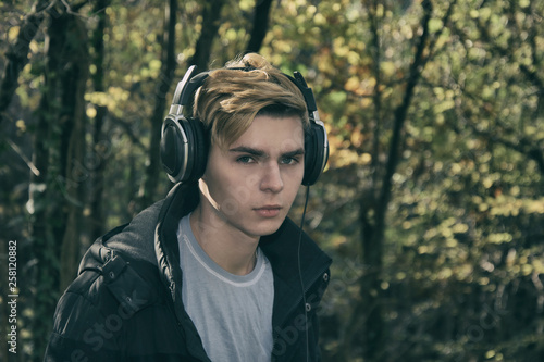 Cold weather. Young attractive guy is resting on the sea and listening to music. © vladorlov