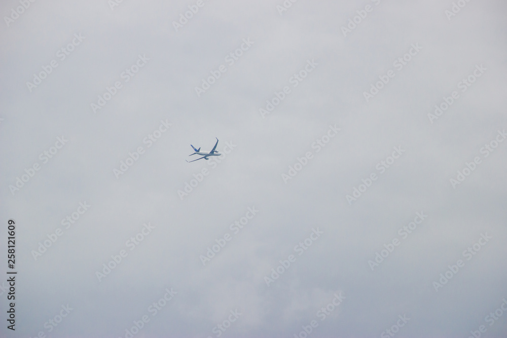 Distant airplane flying in the cloudy sky Distant airplane flying in the cloudy sky