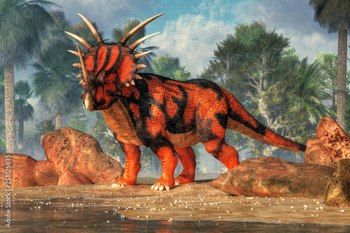 фотографія A red and black sytracosaurus stands on the sandy shores of a cretaceous era lake