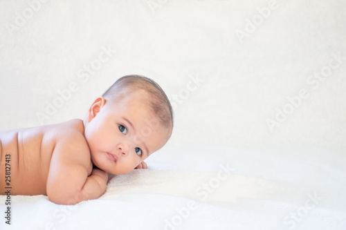 Asian baby girl lying down on bed, shirtless baby
