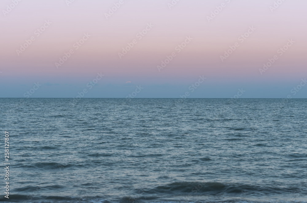 Purple sea and beautiful sky over the sea during sunset with small water ripples.