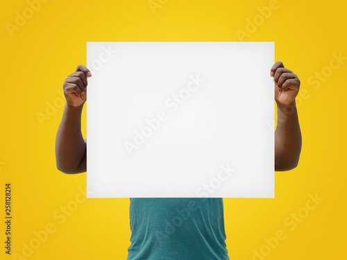 Man holding a blank white sign over his face, isolated on a yellow background