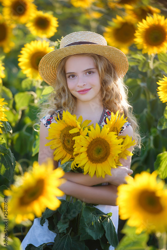 Beautiful young girl enjoying nature on the field of sunflowers at sunset