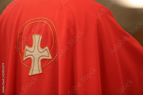 Croix brodée sur une chasuble rouge. / Embroidered cross on a red chasuble. 