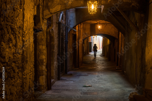Woman walking through the "Rue Obscure" (Hidden Street), Villefranche, south of France © timsimages.uk