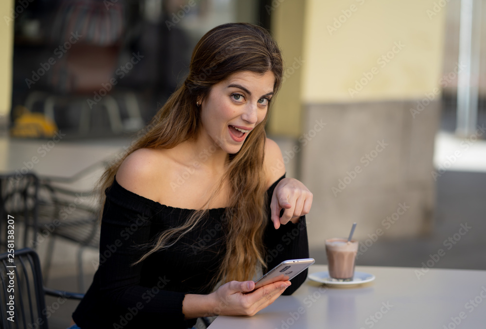 Attractive young woman checking mobile phone happy having lots of followers on her online blog Attractive young woman checking mobile phone happy having lots of followers on her online blog