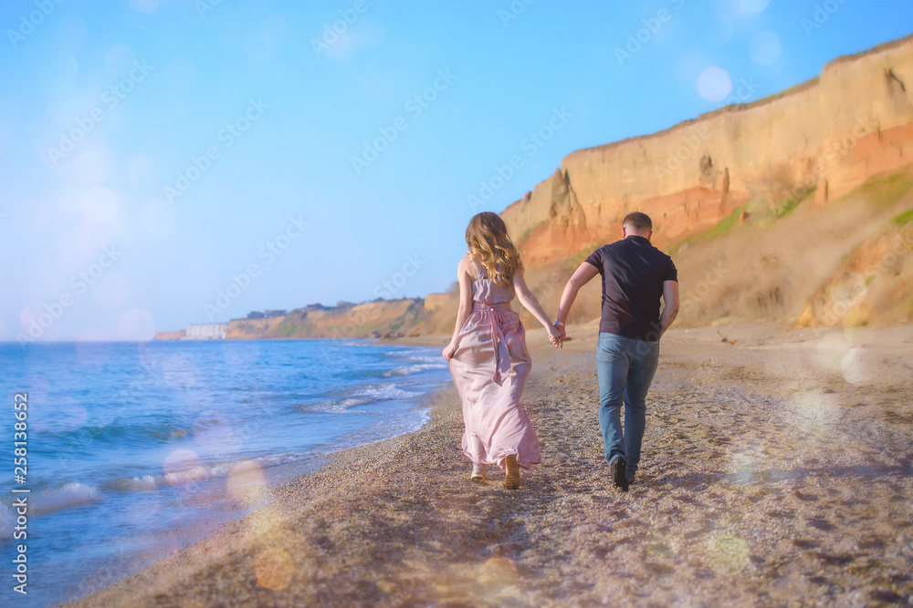 Happy couple runs in wave splashes at romantic sea sunset Happy couple runs in wave splashes at romantic sea sunset