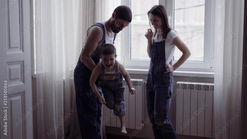cute family standing at the window of a new home. They look out the ...