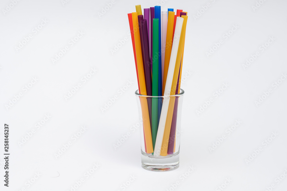 empty glass with colorful straws on a white background