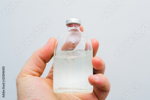 vial with transparent drug solution in a man's hand photo