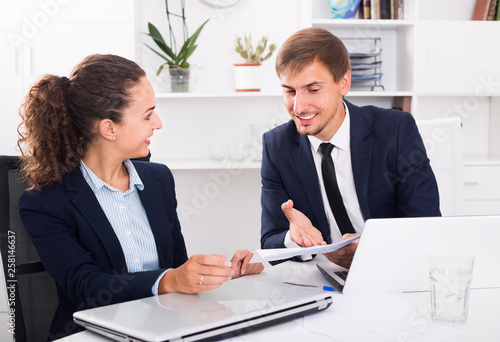 young man and woman coworkers in firm office