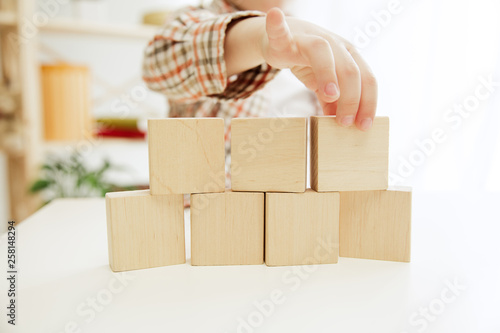 Little child sitting on the floor. Pretty boy palying with wooden cubes at home. Conceptual image with copy or negative space and mock-up for your text photo