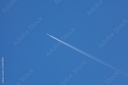  Airplane flying in the blue sky among clouds and sunlight