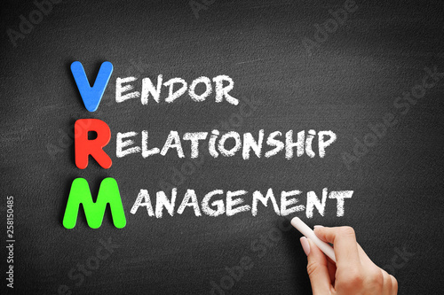 Color Wooden alphabets building the word VRM - Vendor Relationship Management acronym on blackboard