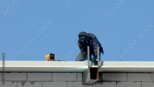 Welder on a building against the sky