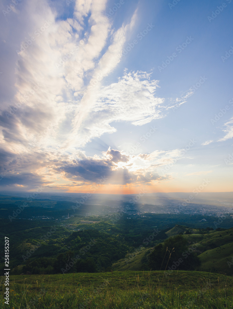 Sunset over Kislovodsk from a height in summer, the rays of the sun through the clouds.